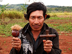 Guarani shaman holding cross and maraca