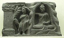 Sculpture of the Buddha holding hand on head monk at the right side of the Buddha, the latter monk smiling