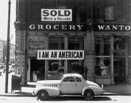 Tatsuro Masuda, a Japanese American, unfurled this banner in Oakland, California the day after the Pearl Harbor attack. Dorothea Lange took this photograph in March 1942, just before his internment.