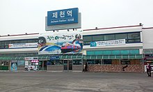 The sign with the name of the railway station in Jecheon -- at the top,a writing in hangul,the transliteration in Latin script below using the Revised Romanization and the English translation of the word 'station',along with the hanja text. Jecheonstation.jpg
