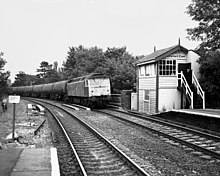 A goods train passing through Knutsford, with the old (now removed) signal box at the north end of platform 2 Knutsford (2321843515).jpg