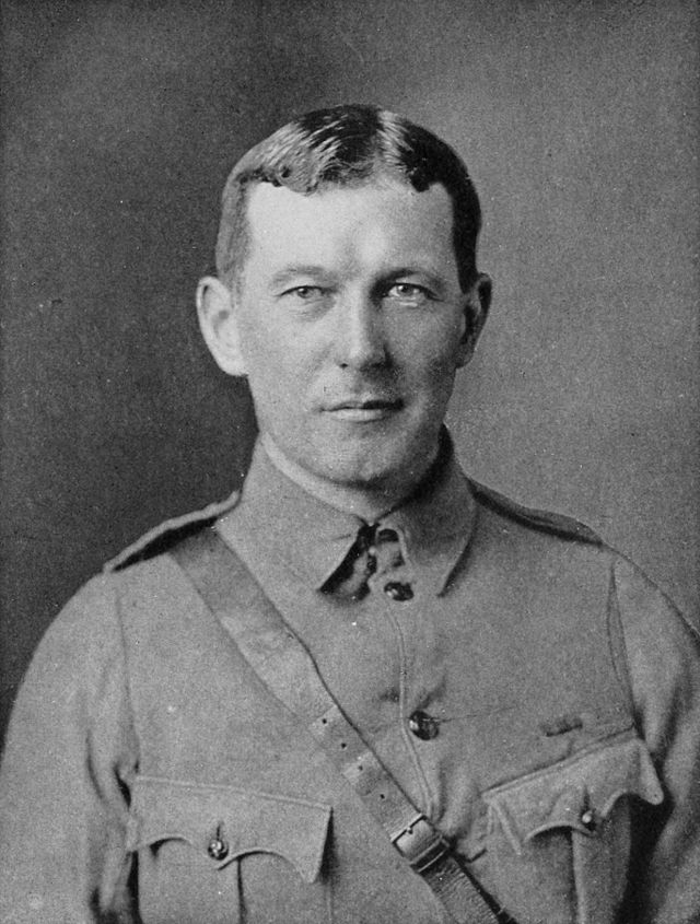 Upper body of a man in a soldier's uniform.  He has short dark hair parted in the middle and maintains a neutral expression.