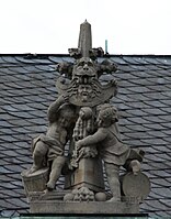 52. Trophäe – Fiale, 2 Putten, Löwenkopf, Löwenpranke, Peltaschild mit Gorgonenhaupt, Goldenes Vlies, Kugeln.