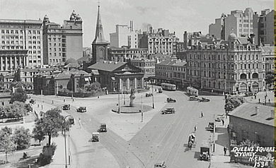 Svart -hvitt foto i luften av krysset mellom Macquarie og King Streets da trafikken fortsatt kunne løpe fra den ene til den andre.  Busser og andre kjøretøyer er på veiene, og den nå revne bygningen på hjørnet kan sees