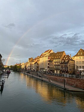 Picture of the beginning of a rainbow in Strasbourg taken from a bridge. The bridge is not visible, the river on which it has been built is however.