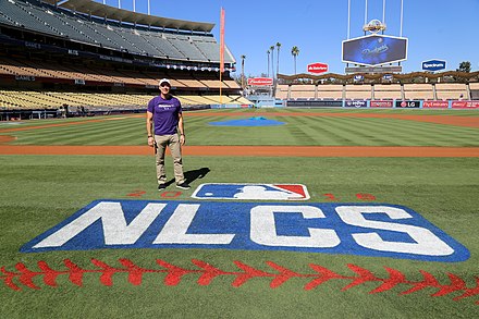 Billy Bean stands by the NLCS logo at Dodger Stadium in 2016