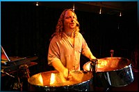 A solo steel drum player performs with the accompaniment of pre-recorded backing tracks that are being played back by the laptop on the left of the photo. Solo steel drummer with backing tracks.jpg