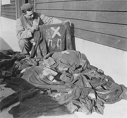 Soldat américain examinant des tenues de déportés NN. Décembre 1944