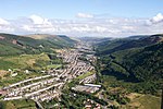 A long continuous settlement comprising long terraced streets extends along a U-shaped valley with forested slopes.