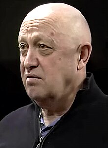Portrait of Yevgeny Prigozhin, bald, looking neutral, wearing a black jacket