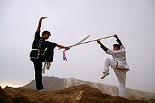 عکس از دو هنرجو رشته کنگفو در ایران در حال مبارزه با شمشیر پهن و چوب (اردیبهشت ۱۳۸۴)