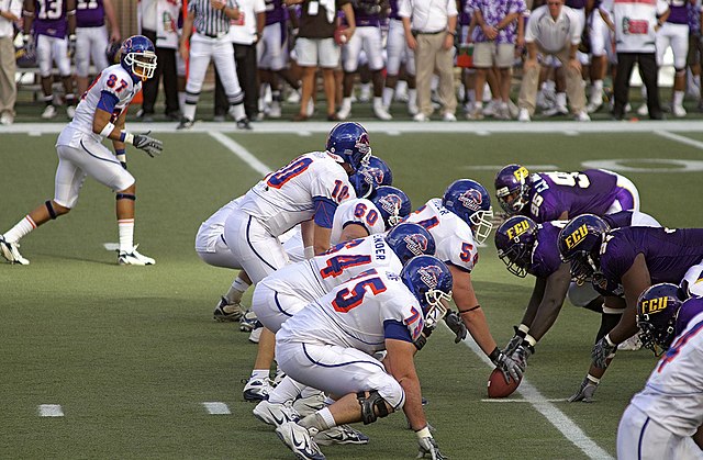 A wide receiver (No. 87, in white) begins a play in the flanker position