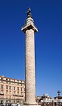 haute colonne blanche, droite et décorée d'une spirale, surmontée d'une petite plate-forme carrée où repose une statue d'homme.