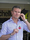 David Coulthard vistiendo una camiseta a cuadros preparándose para una transmisión de medios