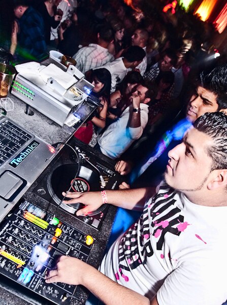 A disc jockey (DJ) mixing vinyl records on turntables (Inland Empire, 2009)