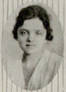 A young woman with wavy dark hair, in an oval frame