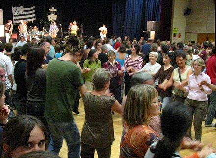 Breton people dancing An Dro, swinging their arms with little fingers linked