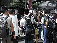 Protesters wearing the "Guy Fawkes masks" from V for Vendetta for protest, a new trend in 2010 HK Causeway Road July 1 march 2010 Mian Ju Ren Mask team members 02.JPG