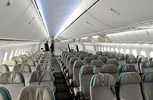 Airliner cabin with two aisles and rows of triple seats.