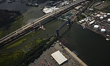 NYC's two barge to rail transfer facilities, on opposite sides of Arthur Kill. On the closer, Staten Island side, blue trash containers from Manhattan and Queens are placed on rail cars at the Howland Hook Marine Terminal. On the New Jersey side, green containers from Brooklyn are trucked to a nearby rail yard. New Goethals Bridge from airplane cropped.jpg