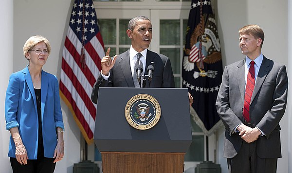 Warren stands next to President Barack Obama as he announces Richard Cordray's nomination as the first director of the CFPB, July 2011.
