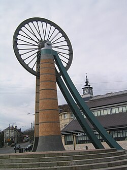 The old coal mining sheave wheel, now featured in the centre of Radstock, in front of the Radstock Museum RadstockMineWheel.jpg