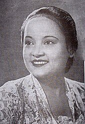 A woman with her hair tied back, looking at the camera and smiling