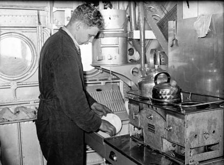 A crew member of a Short Sunderland Mark I of No. 10 Squadron RAAF, washing up in the galley during a flight.
