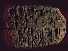 Tablette en argile, divisée en cases comprenant des signes proto-cunéiformes et numériques.