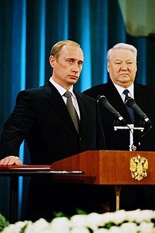 Vladimir Putin takes the oath of office as president on his first inauguration, with Boris Yeltsin looking over, 2000. Vladimir Putin taking the Presidential Oath, 7 May 2000.jpg