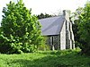 The west end of a flint church with two large buttresses and a slate roof