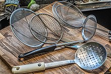 Metal hand-held (ladle-style) skimmers come in a large variety of forms, five of which are shown here. An assortment of various kitchen skimmers.jpg