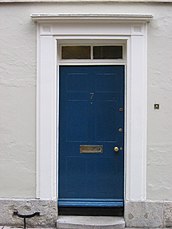 Pilastras simples de madera que forman el dintel de la puerta azul.