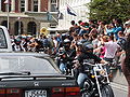 The rest of the parade comes along. On the left is a porn actor showing off his torso, with a female motorcycle driver.