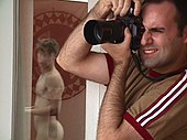 Photo d'un photographe en activité tenant un appareil photo verticalement sur son œil droit.