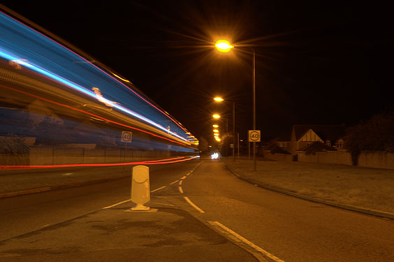 Double-decker First Bus leaving roundabout in Bristol, UK. Lit by sodium-vapor discharge street lights.