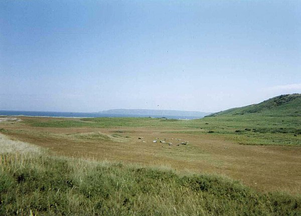 The common in the north of the island. Standing stones can be seen on the grass, while the island of Sark lies in the background.