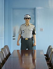 A Republic of Korea soldier of the United Nations Command Security Battalion stands guard inside a JSA conference room, in front of the door leading to the North Korean side of the JSA. View from south to north. InsideTheJointSecurityArea1.jpg