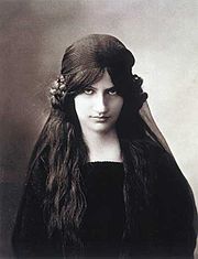 Photo noir et blanc d'une jeune femme en buste de face, vêtue de sombre, l'air à la fois sérieux et mutin sous de longs cheveux