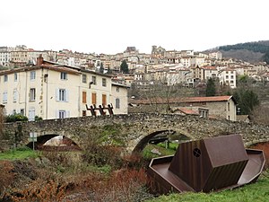 Densely-populated area across a stone arch bridge