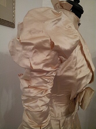 1890s wedding dress made from weighted silk. The splits and damage visible on the sleeve, where the silk fibres have literally 'shattered', have been contributed to in part by the weighting process of the fabric. Shattered silk wedding dress.jpg