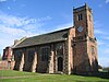 A brick church with a tower on the right incorporating two stone balustrades