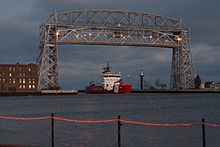 USCGC Mackinaw entering the harbor from the canal, beneath the Aerial Lift Bridge. The rear range light can be seen behind it.