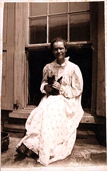 Photograph of Voltairine de Cleyre, wearing a long white dress, holding a cat