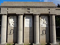 Centralni dio kolonade krase dva Gindertova bareljefa, od kojih je jedan guslar (motiv preuzet sa srušenog Karađorđevog spomenika). Između njih je spomen ploča.