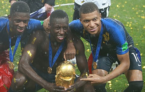 Mendy met Dembélé (l), Mbappé (r) en de wereldbeker na het winnen van het WK 2018.