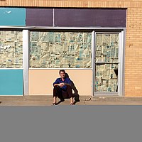 Poet Brian D'Ambrosio sits outside of a colorful abandoned building in rural Texas. Brian D'Ambrosio 2017.jpg