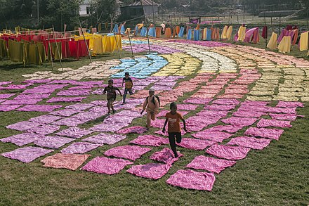 Children playing amongst drying colored cloth in Bangladesh