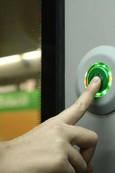 File:Door control button on train with finger.jpg
