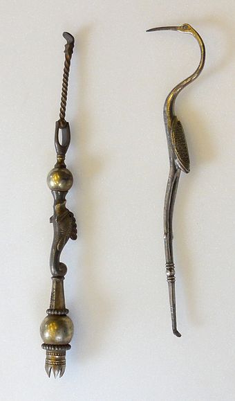 Two toiletry items: one in the shape of a crane-like bird; the other with an empty socket, probably for bristles for a makeup brush